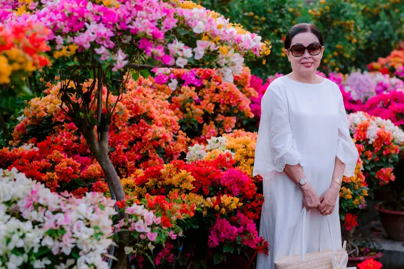 A resident standing among bright bougainvillea in the greenhouse