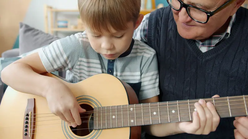 A grandfather teaching his grandson a few chords