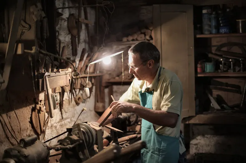 A resident working under the lamp in the woodshop