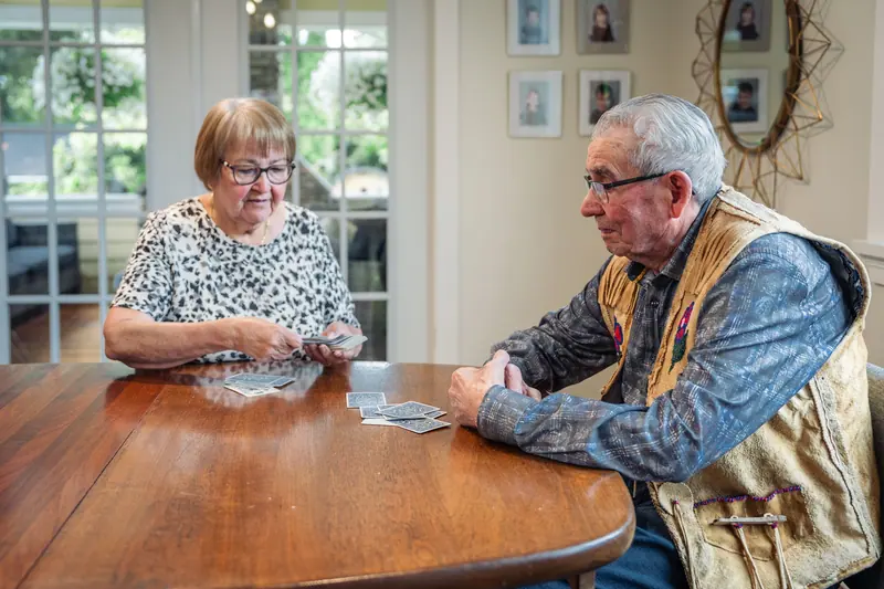 A married couple playing cards at their dining table