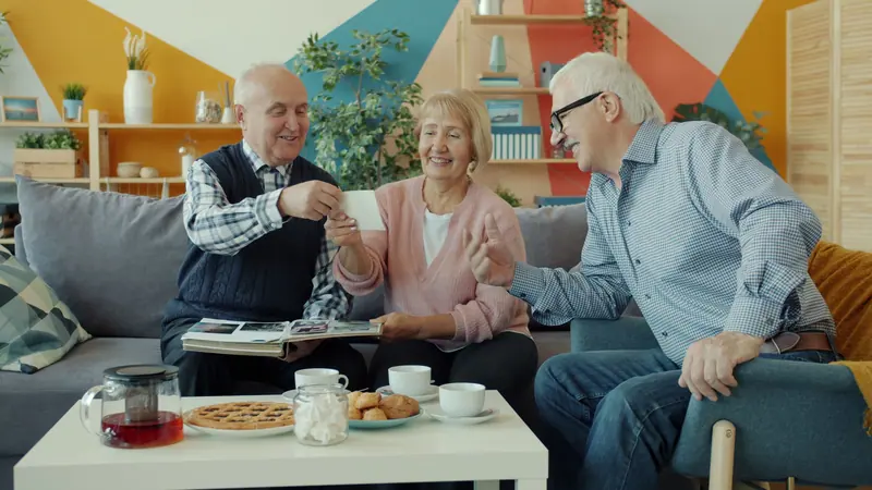 Friends sharing a pot of tea and a card game on the couch