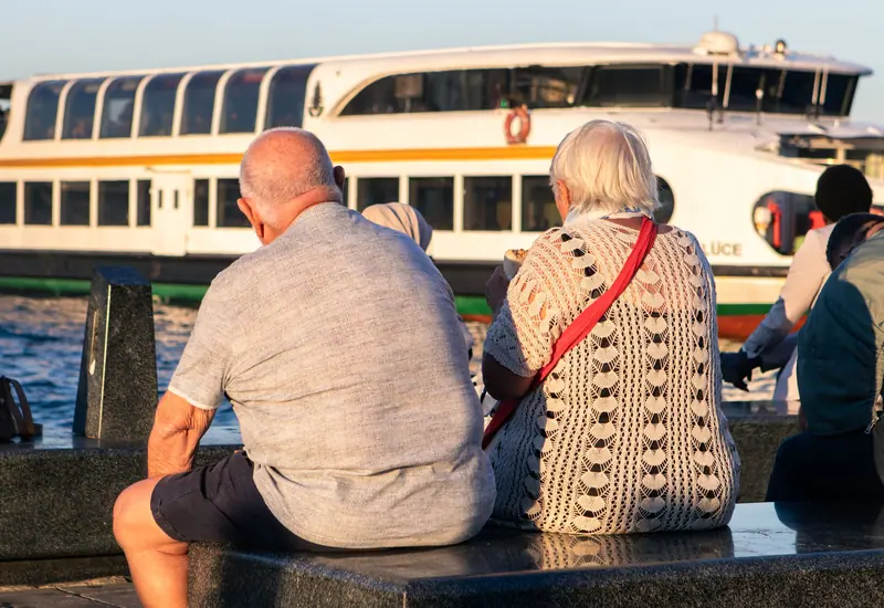 Residents watching a boat pass from the waterfront bench
