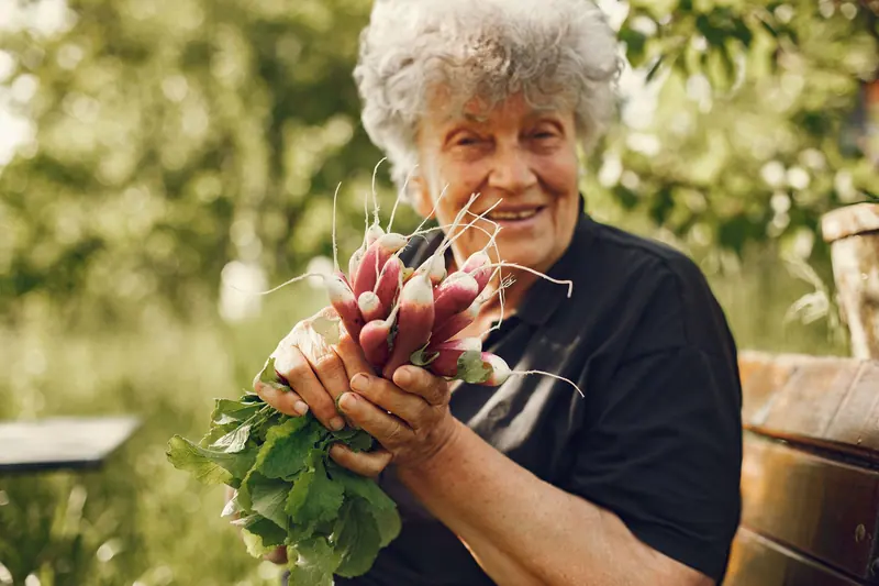 A smiling resident holding a bunch of radishes she just pulled from the garden