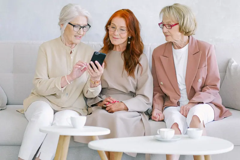 Three neighbors looking at photos on a phone in the lobby