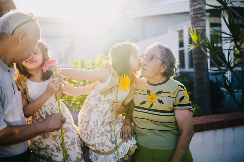 A resident sharing a laugh with her granddaughters in the sunshine
