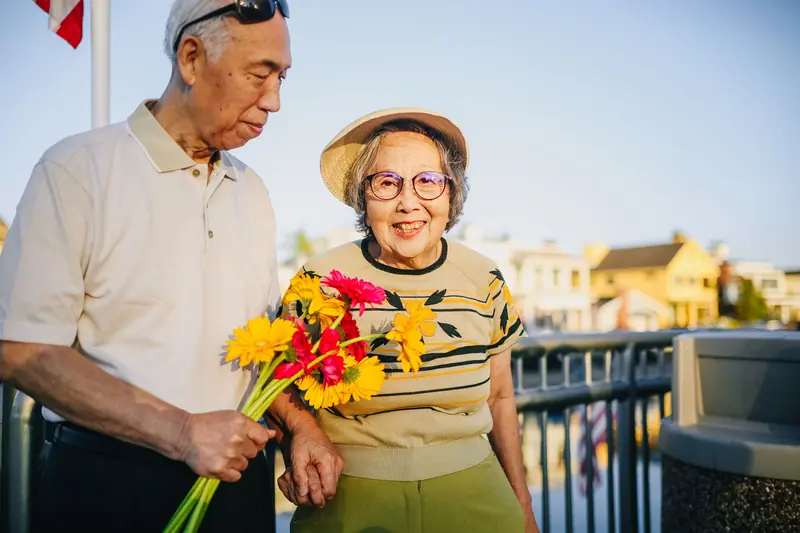 A resident and her husband holding a bouquet from the cutting garden