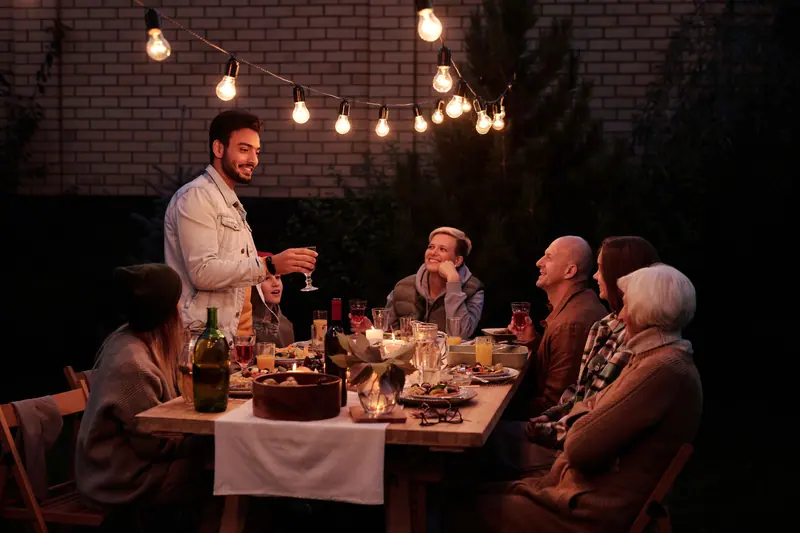 Residents and families at the long table under the string lights