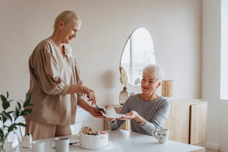 A resident passing a plate of cake across the tea table