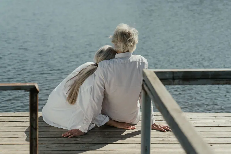 A couple sitting close together at the end of the dock