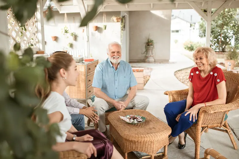 Residents relaxing in wicker chairs on the covered patio