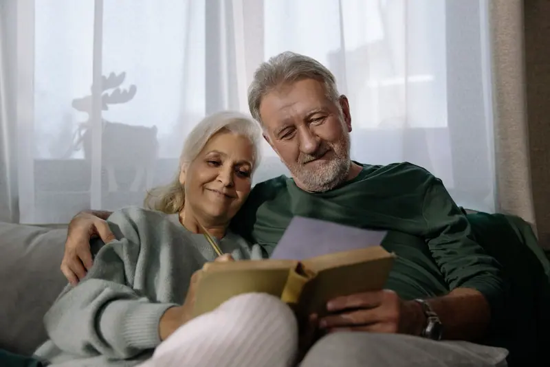 A couple reading together under a blanket on the sofa