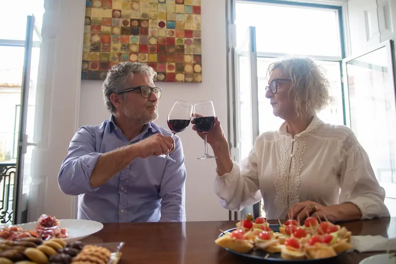 A couple toasting over a plate of appetizers