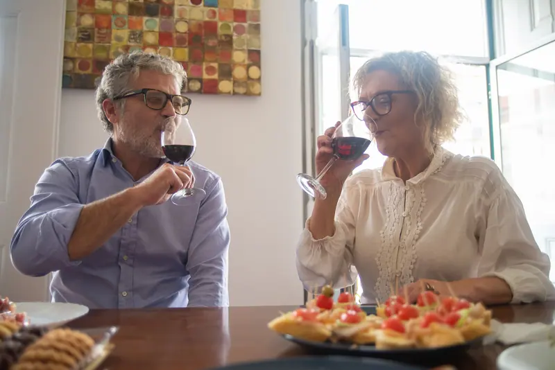 A couple sharing appetizers and red wine at a window table