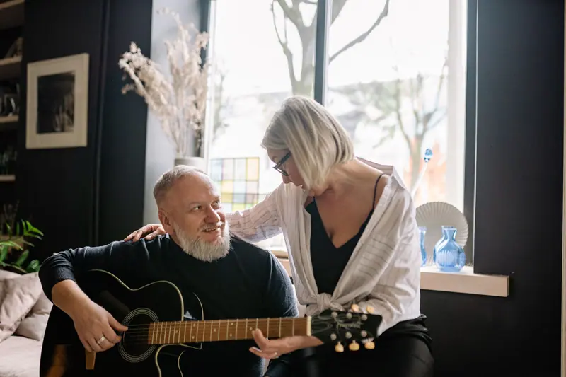A resident playing guitar for his wife in their sitting room