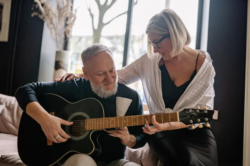 A resident playing guitar while his wife leans in to sing along