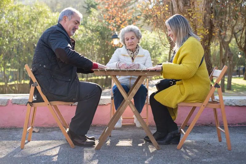 Friends playing cards at a folding table in the park