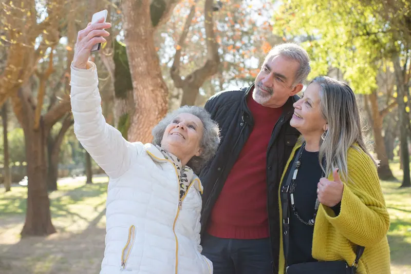 Three friends taking a selfie under the fall trees