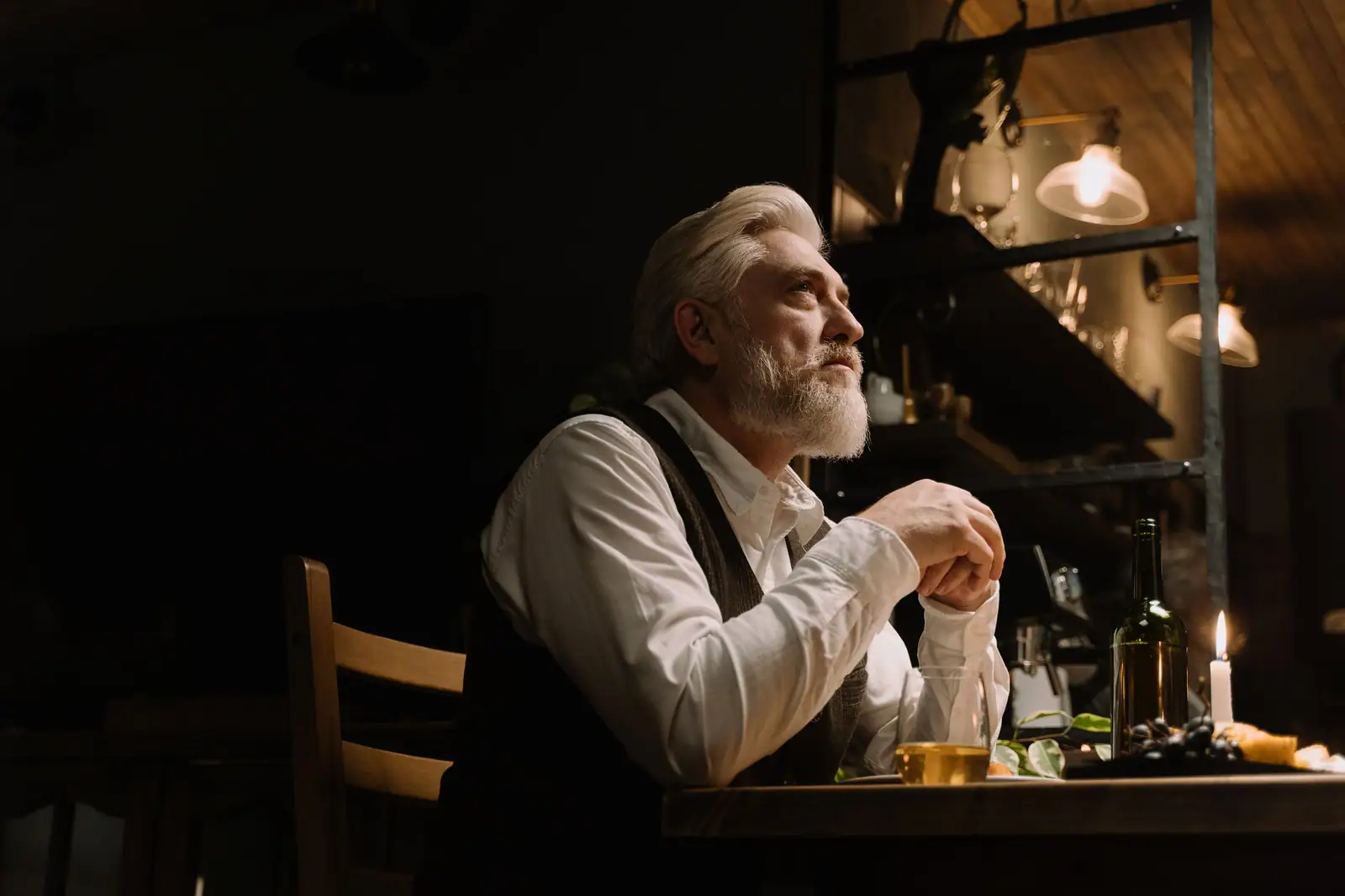 Senior man enjoying a quiet meal by candlelight in a cozy and elegant indoor setting.