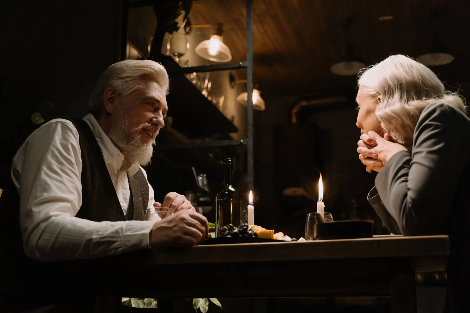 An older couple sharing a quiet candlelit supper at a table set with bread and wine