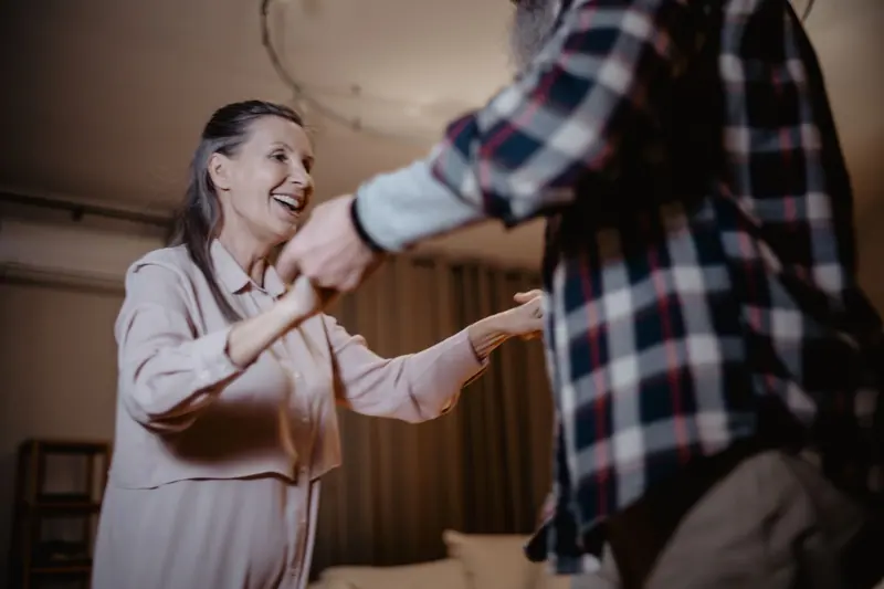 A couple dancing and laughing in their apartment living room