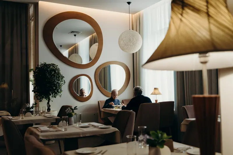 The ballroom dining room set for the evening, with round mirrors and warm pendant lights