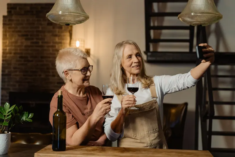 Two neighbors toasting with red wine at the kitchen island