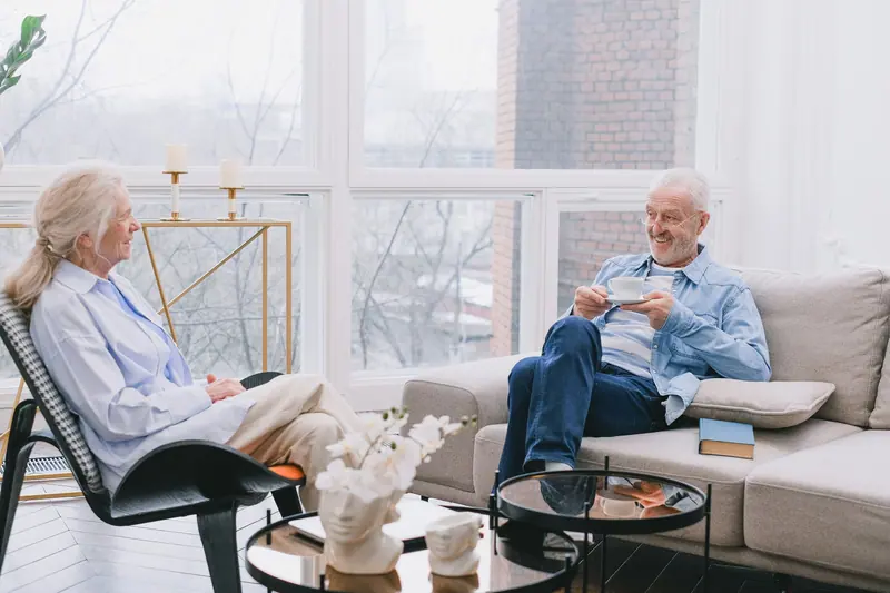 A couple chatting over tea in their sunlit apartment living room