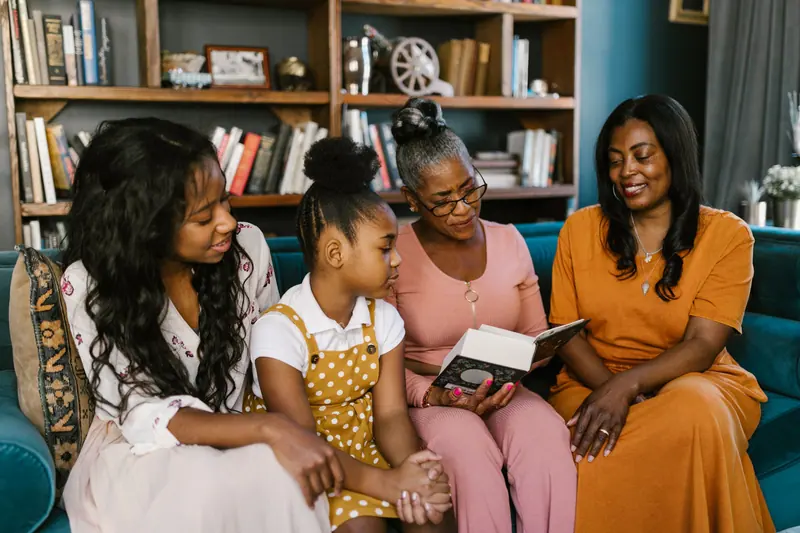 A grandmother reading with her daughters and granddaughter