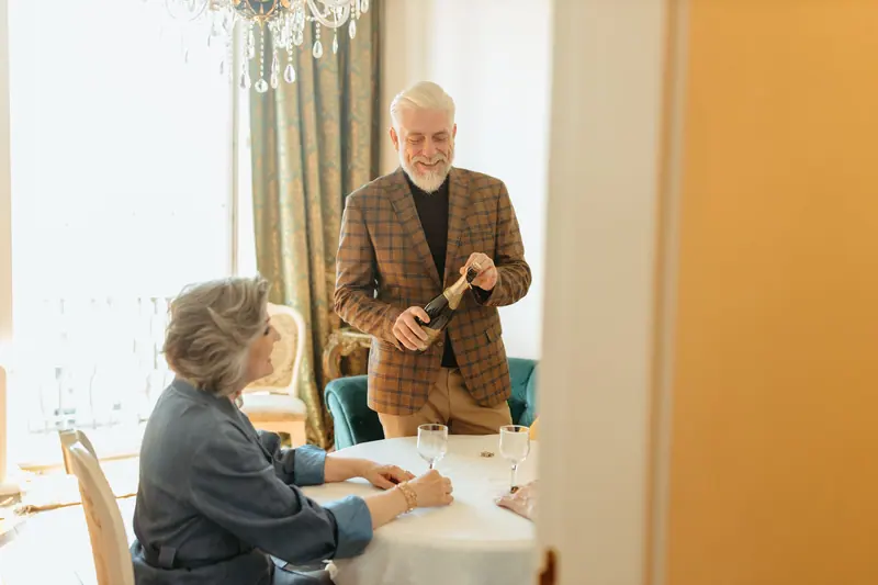 A resident pouring champagne for his neighbor at a celebration supper