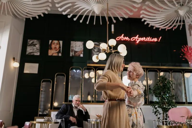 Two friends dancing in the café while a neighbor watches