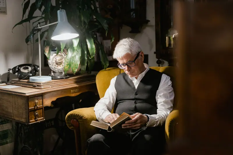 Reading under a desk lamp in the study
