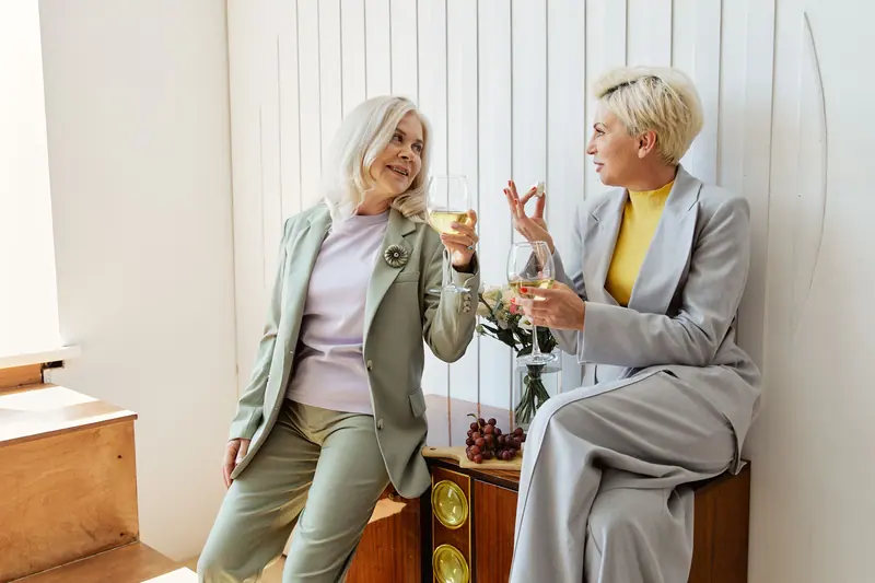 Two friends sharing a glass of wine and a story by the window