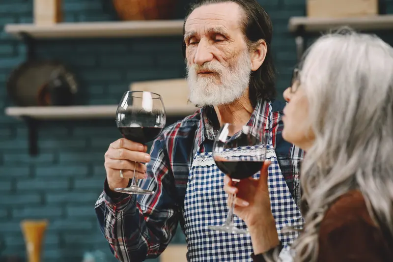 A couple laughing over a glass of wine while cooking together