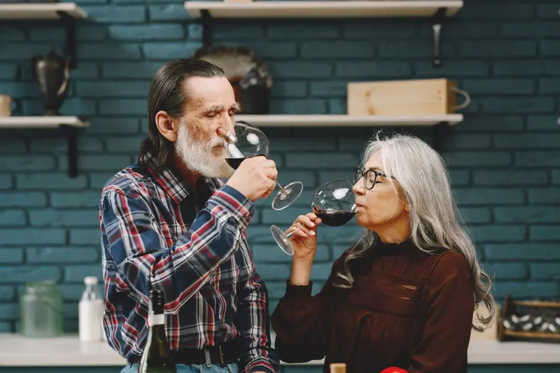 A couple tasting red wine in the kitchen of their cottage