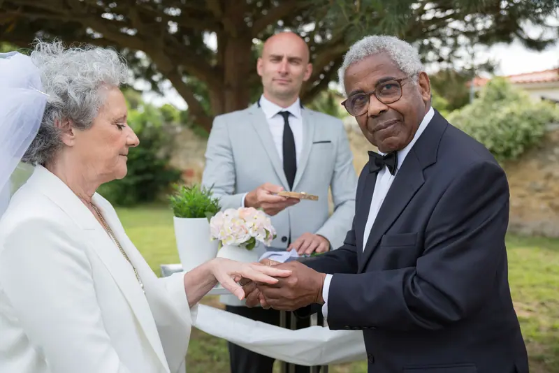 A couple renewing their vows in the garden, with family looking on