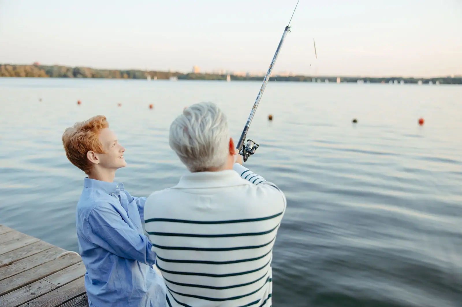 A grandfather casting from the dock while his grandson watches the line