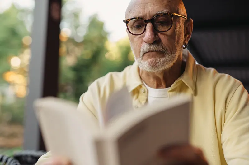 A resident absorbed in a paperback on the porch