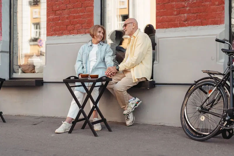 Two friends sharing coffee on a sidewalk bench