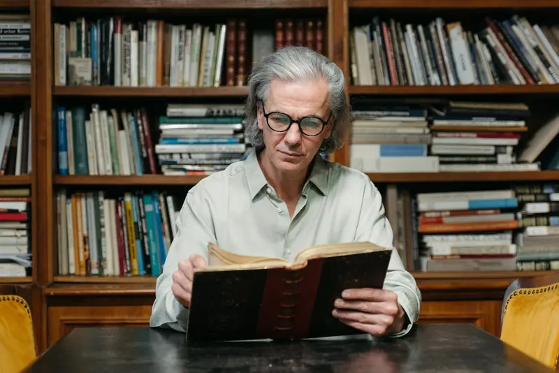 A resident deep in an old book at the library table
