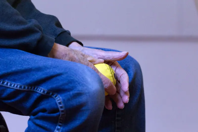 A patient squeezing a stress ball to rebuild grip strength