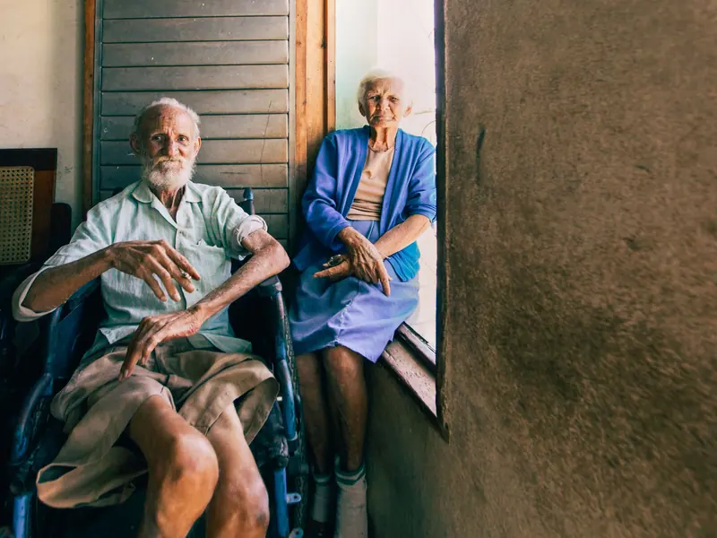 A married couple sitting together by a sunny window, one in a wheelchair