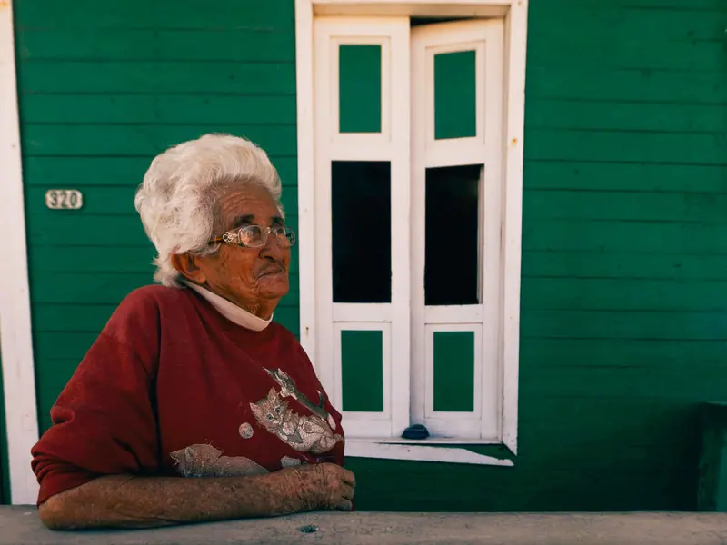 A resident in a red sweater resting her arms on the porch rail