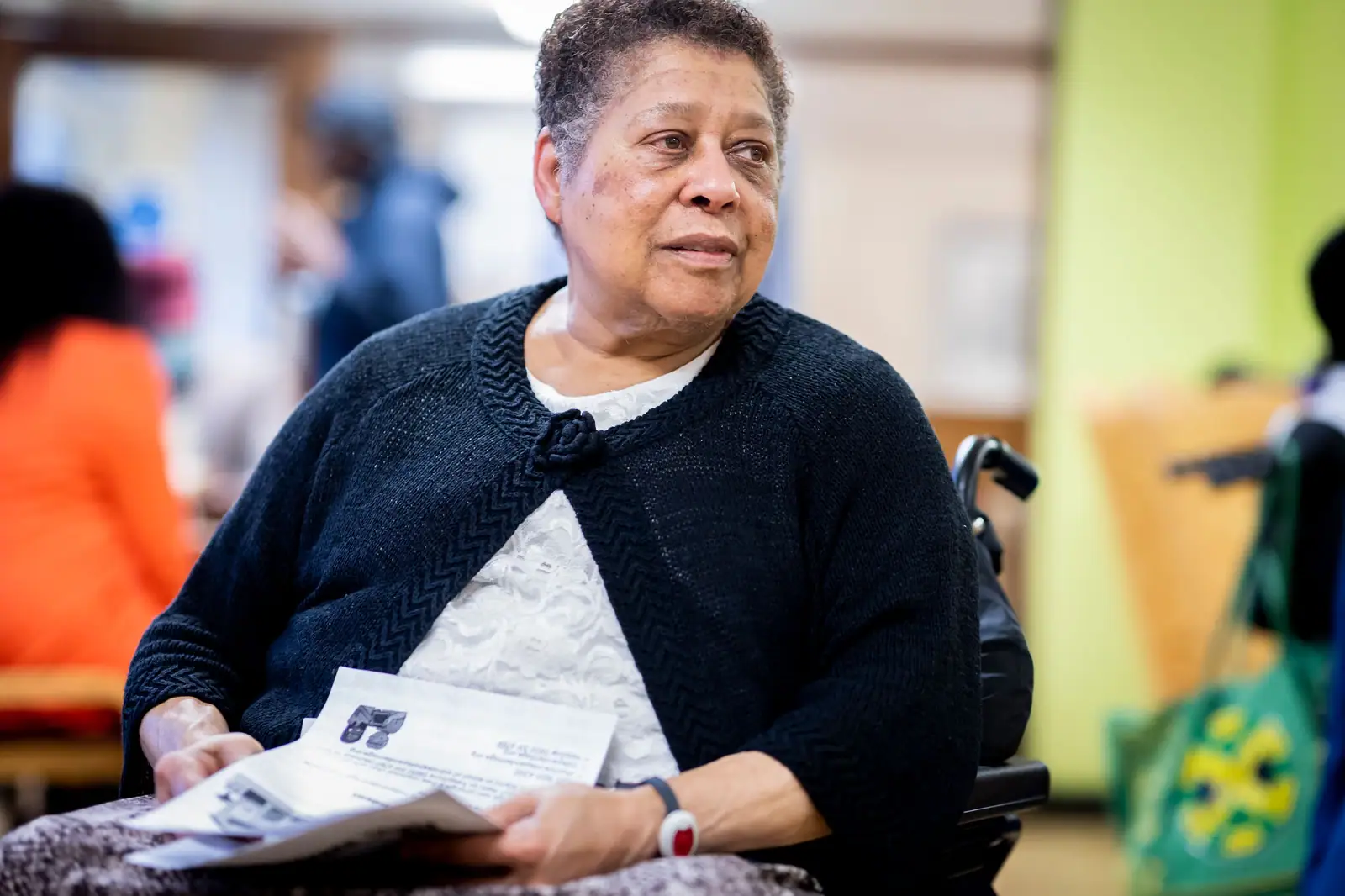 A resident in a cardigan reading the afternoon paper in the day room