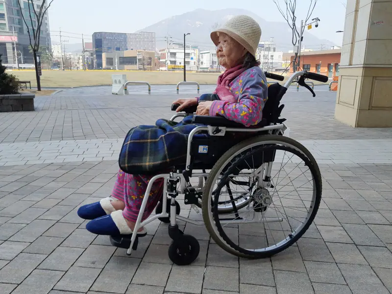 A resident in a pink jacket enjoying the sun on the front plaza