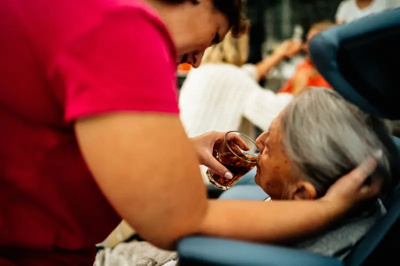 An aide helping a resident with a cup of tea