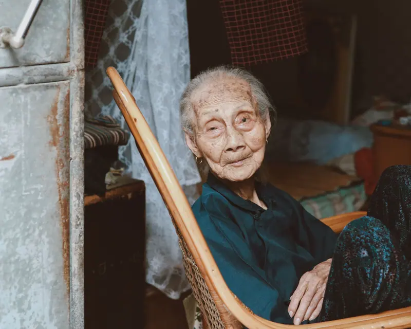 A resident resting in a rocking chair by her window