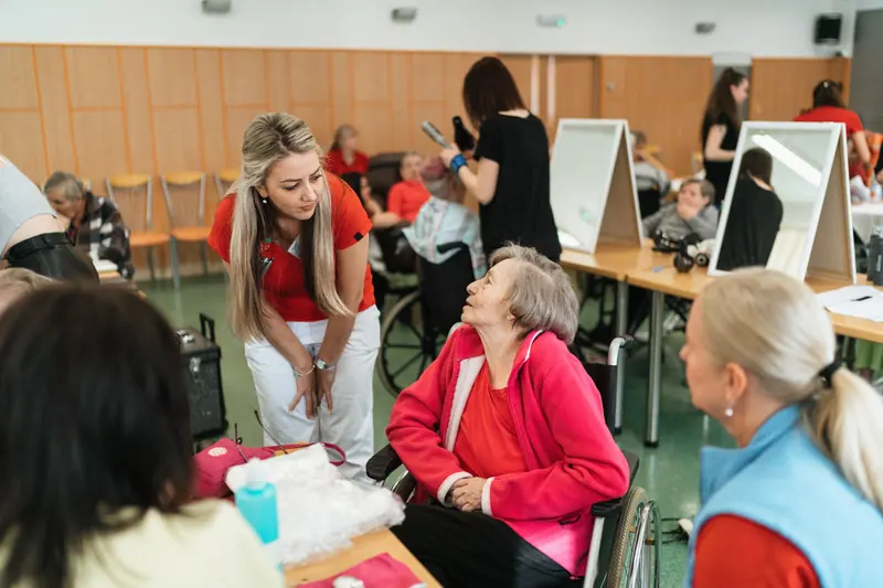 An aide leaning in to talk with a resident during an activity