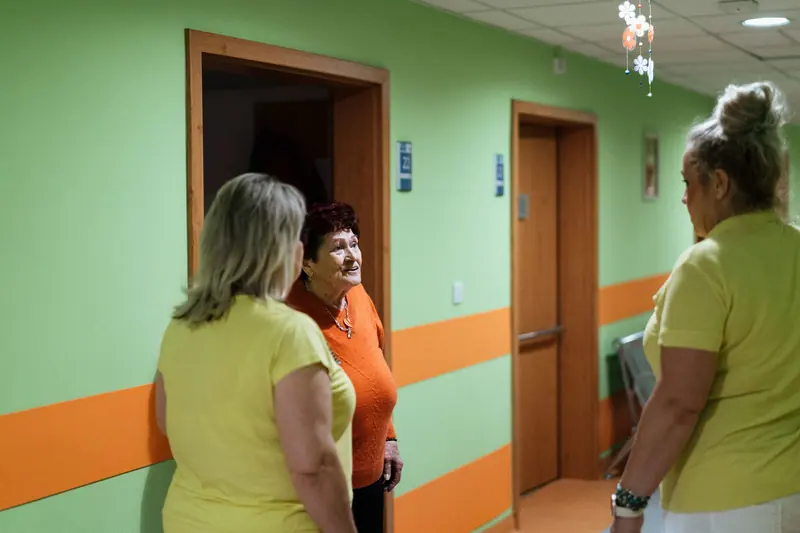 A resident chatting with two aides in the hallway