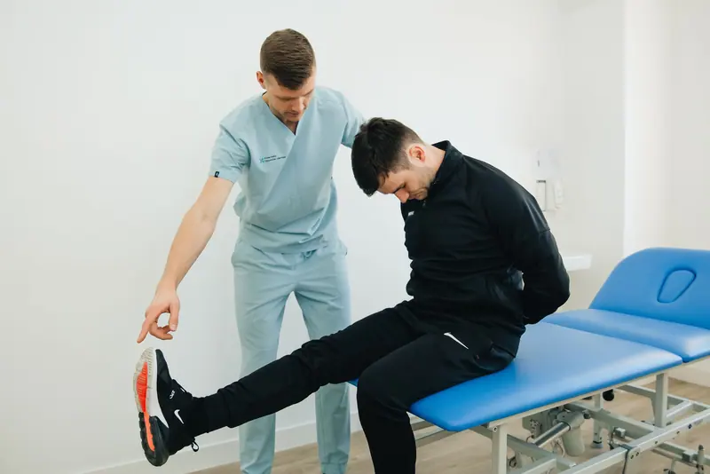 A physical therapist guiding a patient through a leg stretch on the mat table