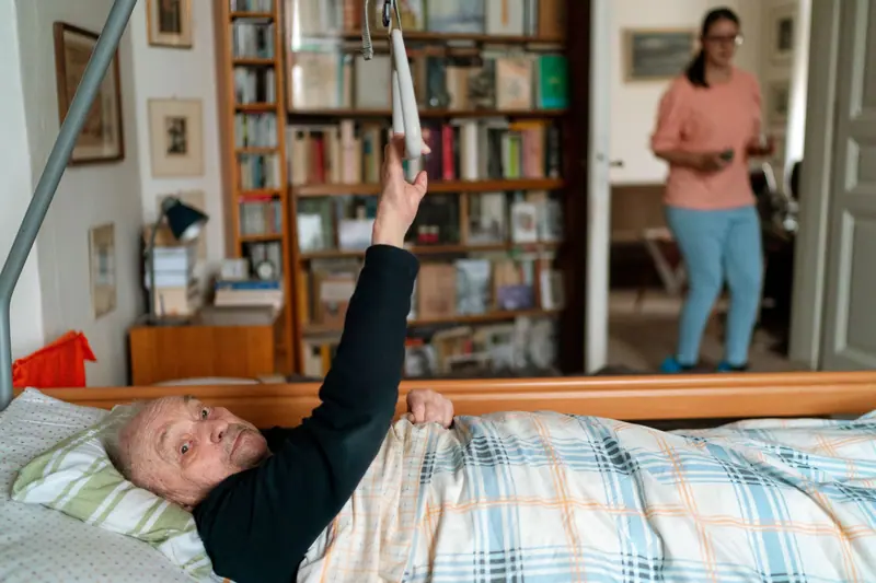 A resident reaching for a book from bed